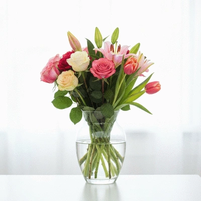 Vase en verre avec un bouquet de fleurs colorées, style minimaliste, fond clair