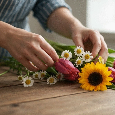 Gros plan sur des mains arrangeant des fleurs locales et de saison